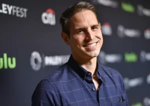 A photo of Greg Berlanti, wearing a dark suit and tie, smiling at the camera on a red carpet, highlighting his role as a leading TV producer and showrunner in 2025.